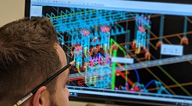 Man looking at computer screen with pencil behind ear