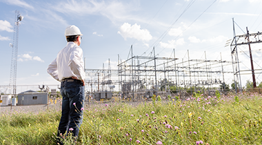 Man in field looking at electrical station