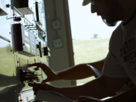 Man in hard hat inspecting panel in the field